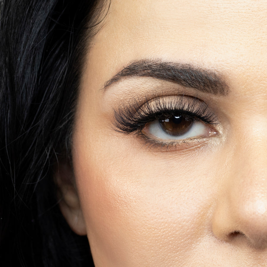 Suntarah Beauty 3D Faux Mink False Strip Eyelash in Style F-105. Close up f young woman wearing lash looking straight ahead. Lash has a wispy and foxy look.